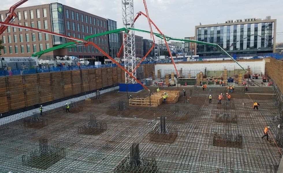 Wide view of an urban construction site showing reinforced concrete foundation