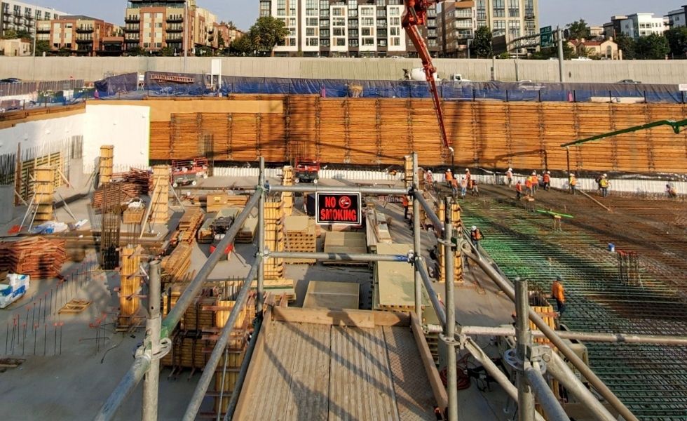 Overview of a deep excavation site where workers prepare reinforcement