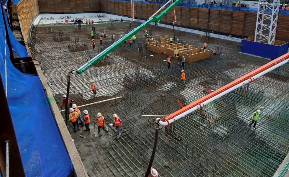 Construction workers placing steel reinforcement and pumping concrete