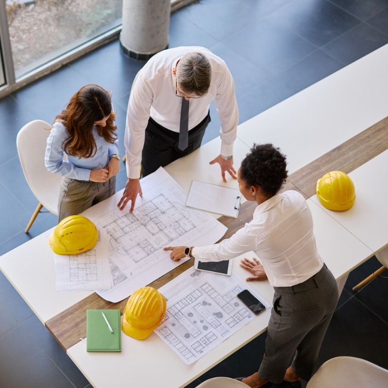 Two architects and an engineer reviewing architectural blueprints 