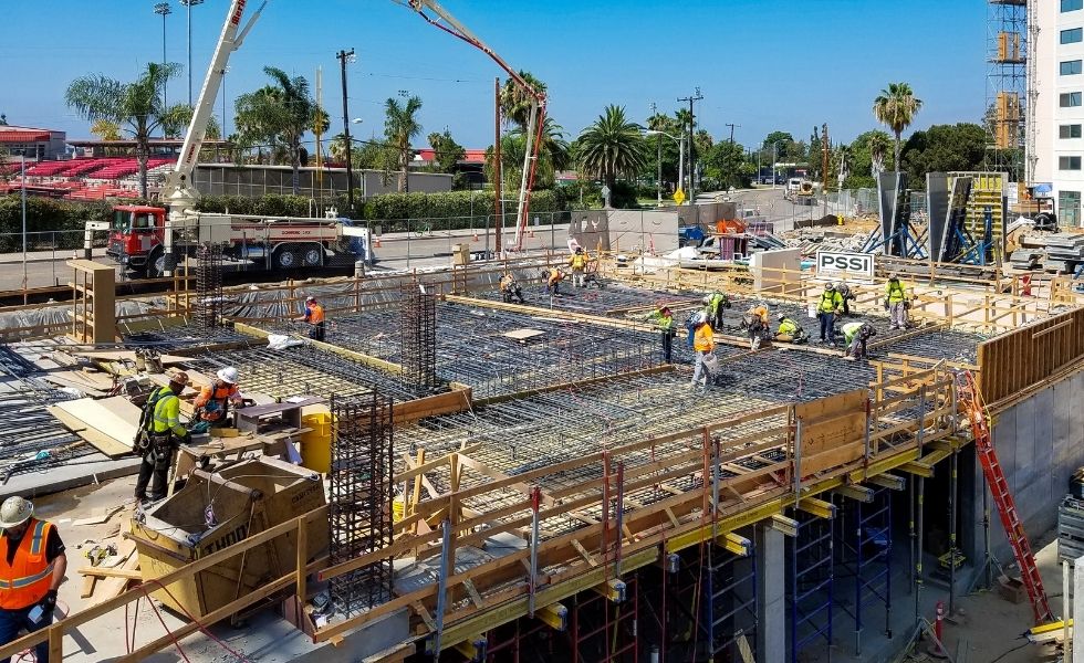 Construction workers installing rebar reinforcement and preparing concrete slab placement on an elevated structure