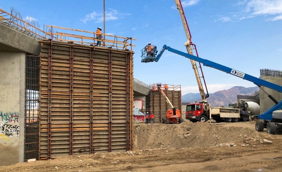 Construction crew working on bridge pier formwork with reinforcing steel