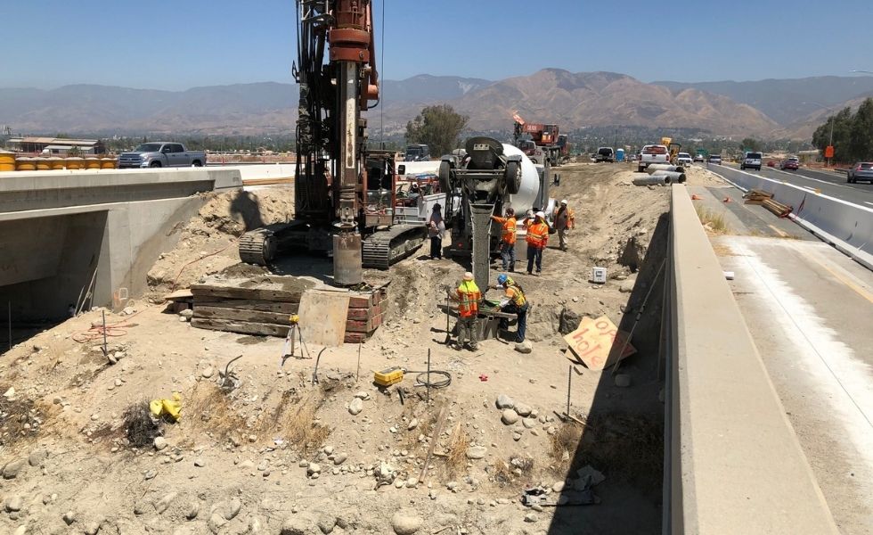 Construction site showing a drilling rig and crew performing drilled shaft