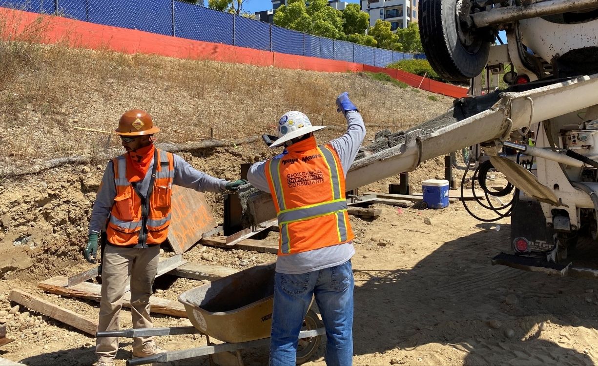 Wide view of an active construction site with a large drilling rig preparing caisson foundations