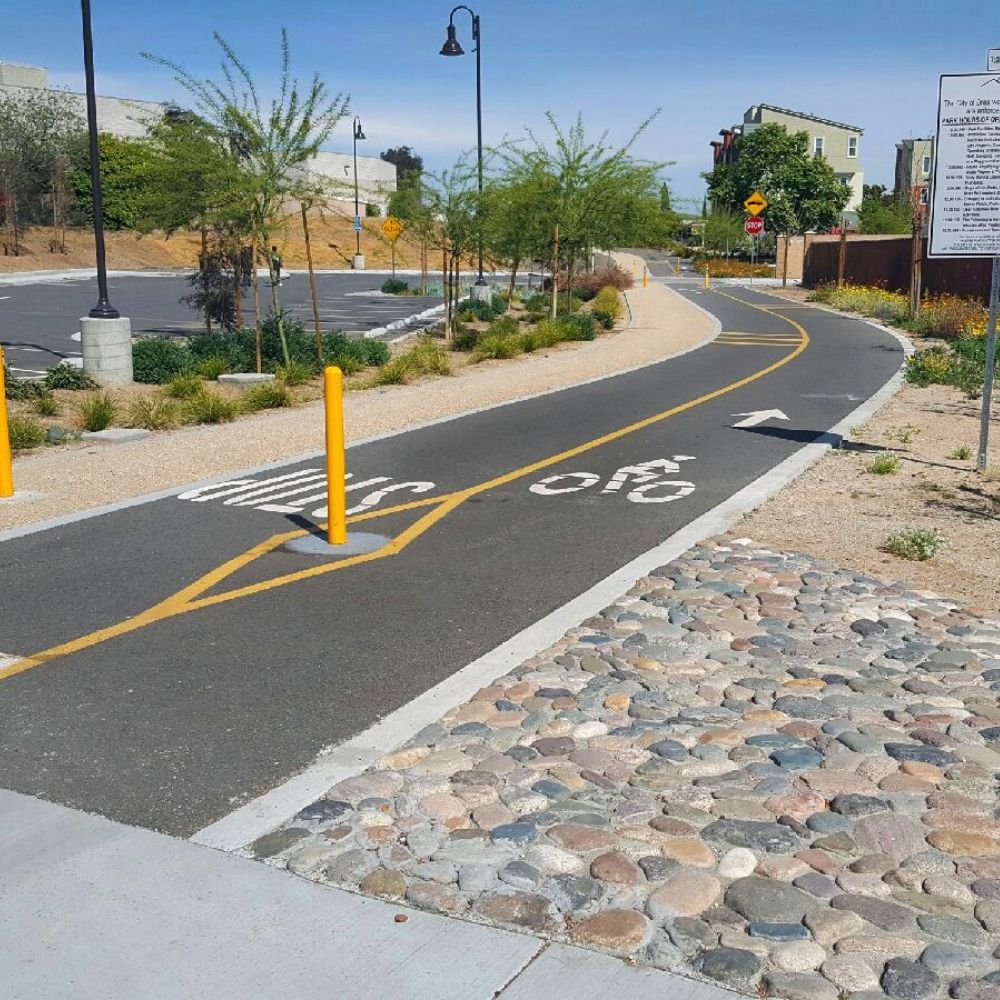 A paved, curved bike lane with directional arrows and a bicycle symbol