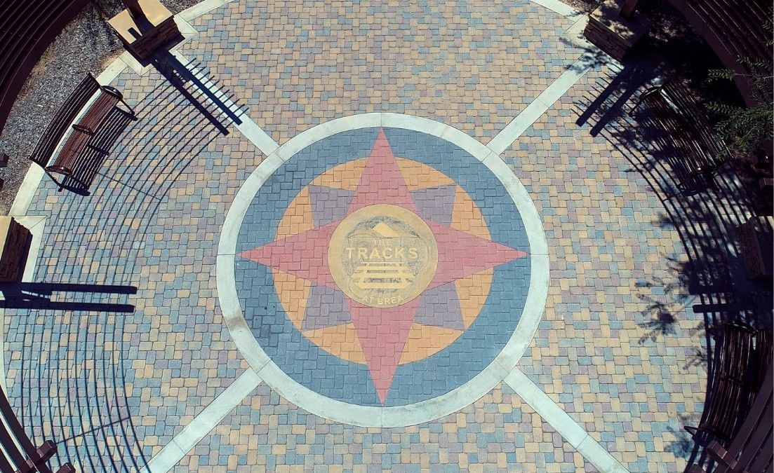 Overhead view of a circular paved plaza featuring a large compass-style design