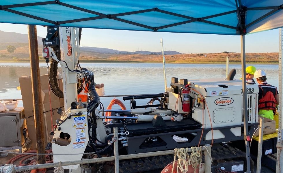 Close-up of geotechnical drilling equipment installed on a floating work platform over a reservoir