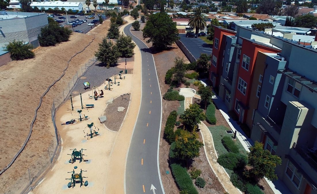 Aerial view of a paved bike path running through a landscaped urban corridor