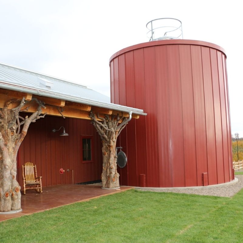 Angry Orchard Cidery production facility featuring a red cylindrical processing structure connected to a barn-style building