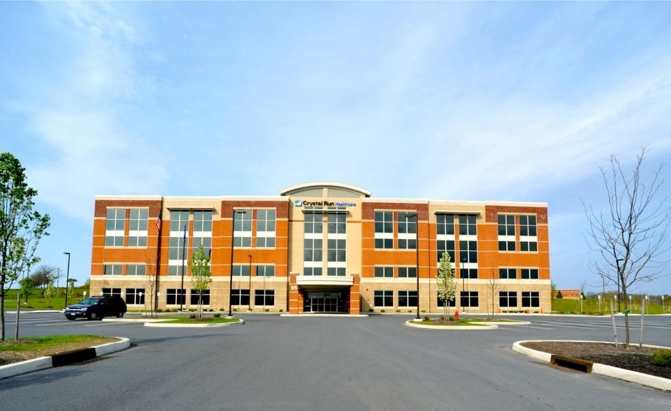 Front view of the Crystal Run Healthcare medical office building in New York, featuring a three-story brick and glass façade
