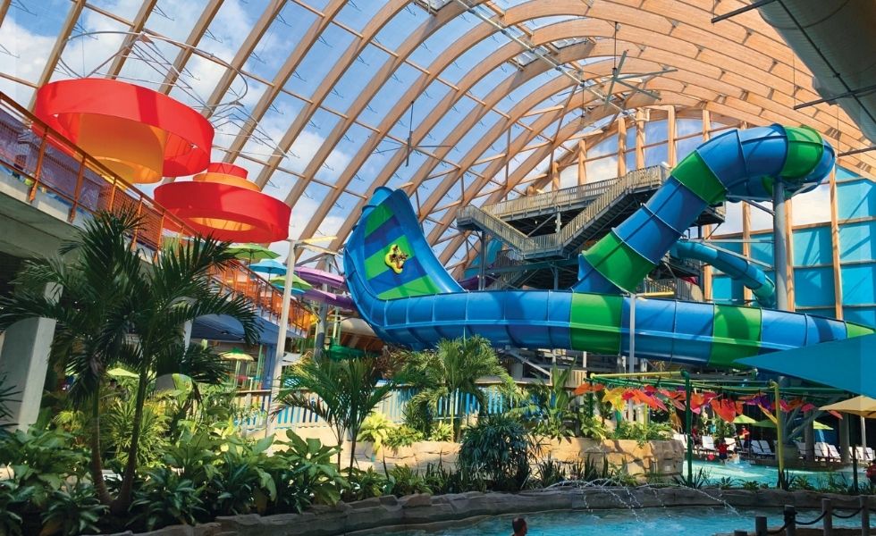 Interior view of The Kartrite Resort & Indoor Water Park, NY, showcasing enclosed water slides, aquatic attractions, tropical landscaping