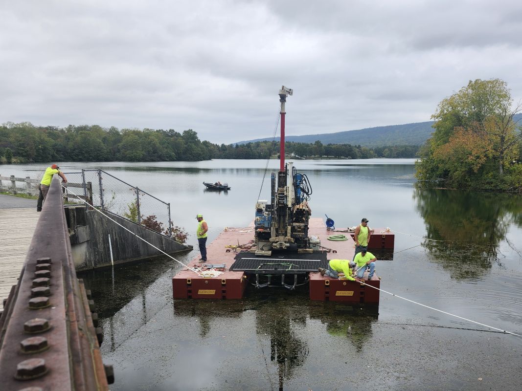 geotechnical engineers inspecting core drilling on barge for dam upgrade