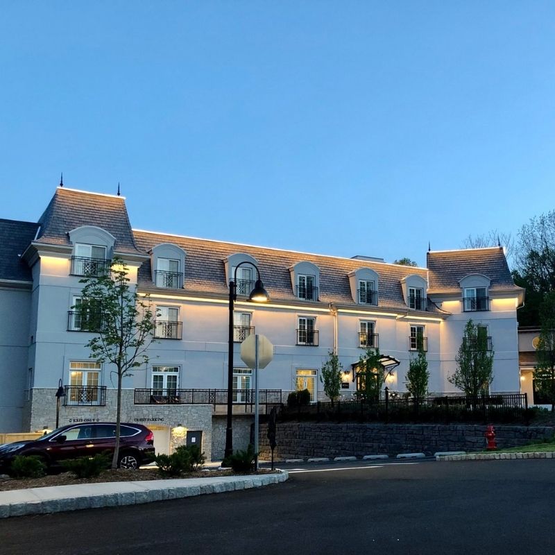 Evening exterior view of the Mirbeau Inn & Spa in Rhinebeck, New York, featuring the illuminated hotel façade, main entrance, and landscaped grounds.