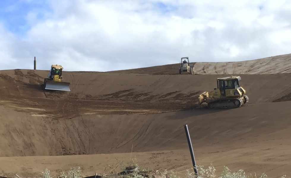 Bulldozers and grading equipment shaping an engineered basin during earthwork construction at the PhilaPort Auto Storage Facility.