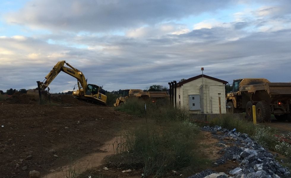 Excavator and articulated dump trucks performing excavation and earthmoving operations at the PhilaPort Auto Storage Facility project.