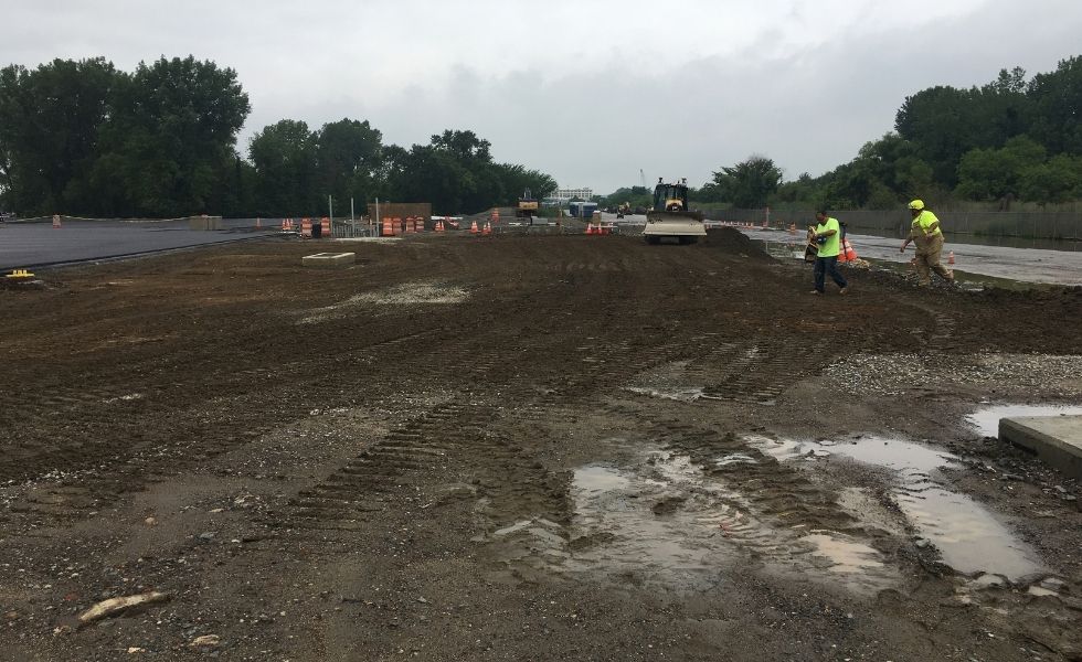 Construction site undergoing grading and earthwork activities at the Philaport Auto Facility project, showing heavy equipment, temporary traffic control devices.