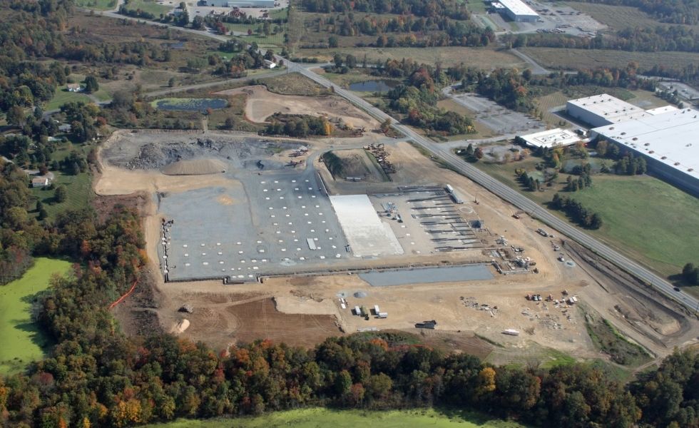 Aerial view of the United Natural Foods Distribution Facility construction site in Wallkill, New York, showing foundation work, site grading, stormwater features, access roads.