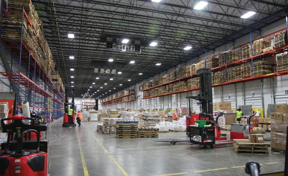 Interior of the United Natural Foods Distribution Facility showing warehouse operations, pallet storage racks, forklifts, loading areas.