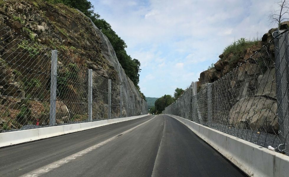US 11/15 Rock Slope Safety Improvement, PA project: completed roadway corridor with installed rockfall protection fencing and slope stabilization systems along both sides of the rock cut.