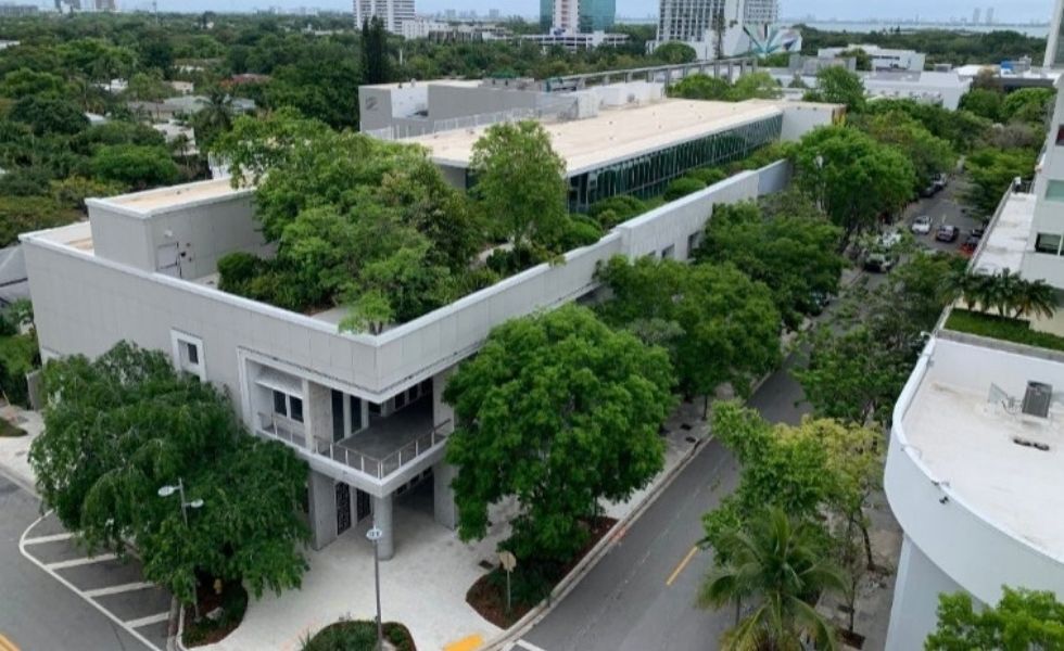 Aerial view of a modern building within the Miami Design District LEED-ND Gold Certification Project, featuring a landscaped rooftop with mature trees.