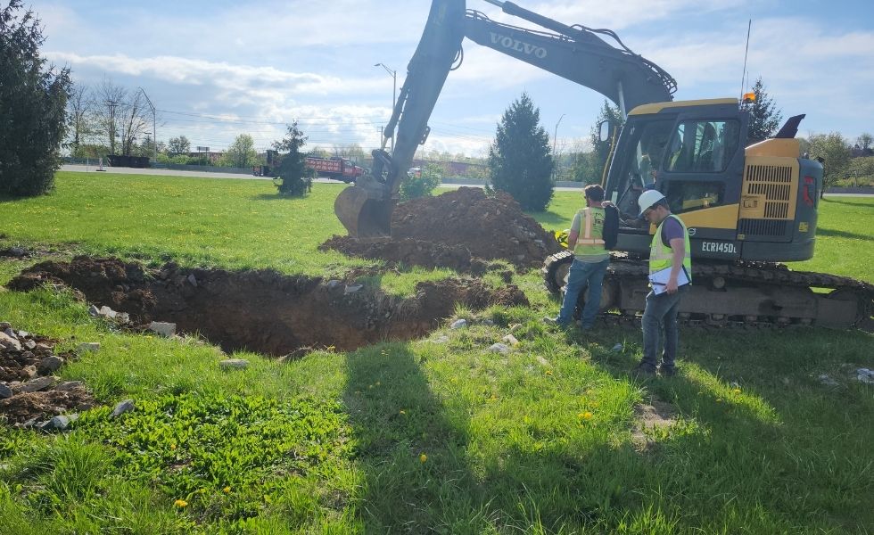 Field excavation activities performed as part of the Open-End Geotechnical Services Contract, showing an excavator and engineering personnel evaluating exposed subsurface