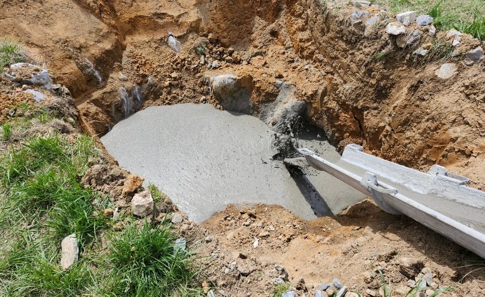 Concrete grout being placed into an excavated sinkhole remediation area as part of the Open-End Geotechnical Services Contract, showing ground stabilization activities used to address subsurface voids