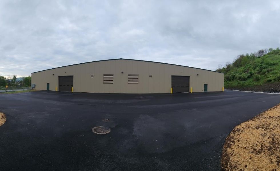 View of the maintenance garage and paved service yard at the STEP Williamsport Transportation Facility in Pennsylvania, showing a large operations building