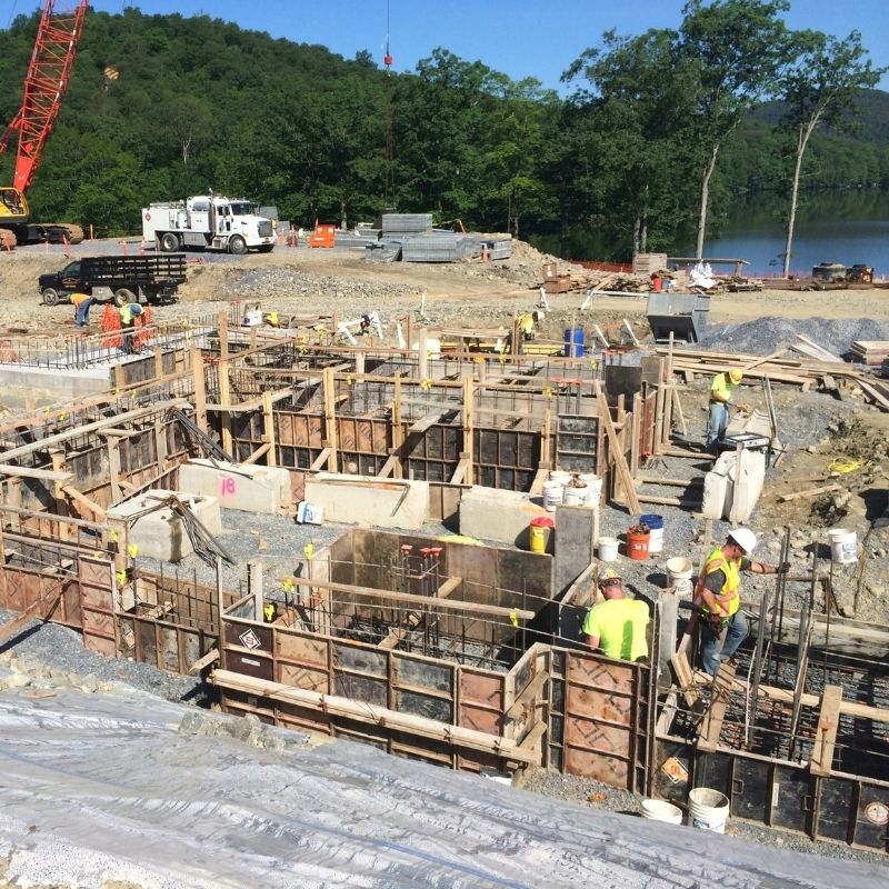 World Headquarters Construction project site showing foundation work, concrete formwork, reinforcing steel, construction workers, heavy equipment, and cranes.