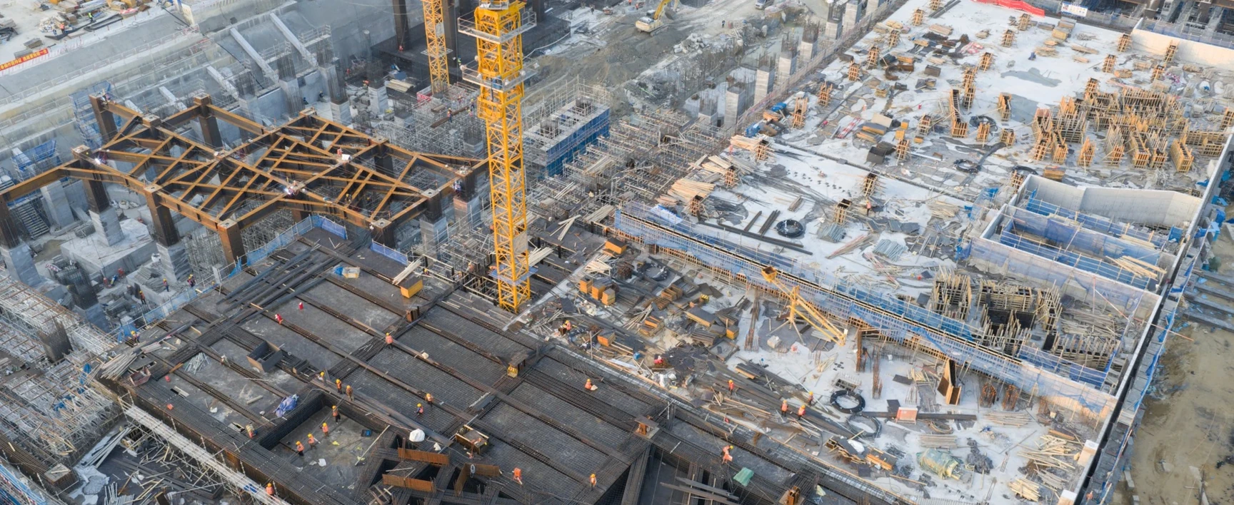 Aerial view of a large infrastructure construction site featuring cranes