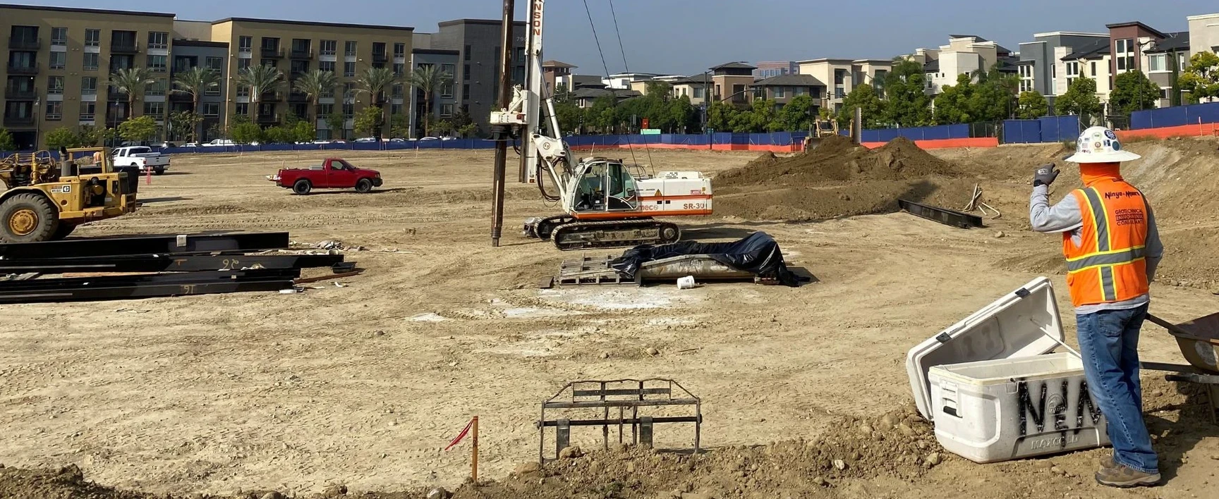 Track-mounted geotechnical drilling rig operating at a large construction site