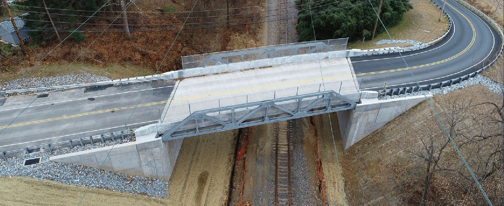 Aerial view of the completed Howellville Road Bridge Replacement project in Pennsylvania, showing a new bridge structure carrying a two-lane roadway over a railroad corridor.