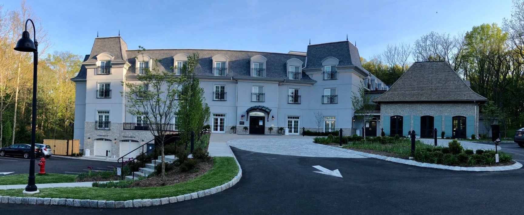 Front exterior view of the Mirbeau Inn & Spa hotel and spa facility in Rhinebeck, New York, showcasing the main entrance, landscaped grounds, and guest accommodations.