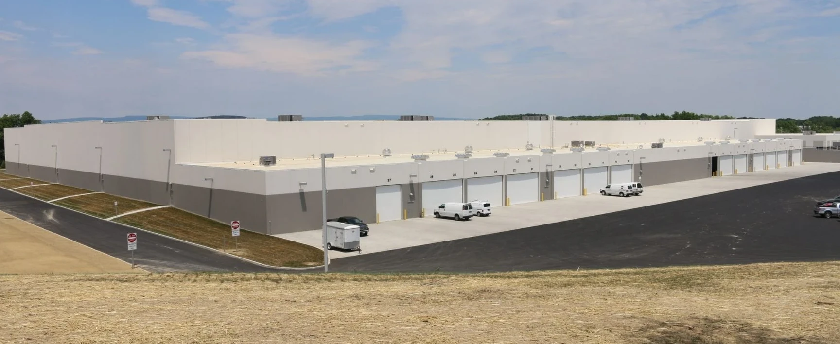 Aerial view of the PharmaCannis Medical Marijuana Facility in Hamptonburgh, New York, featuring a large industrial research and manufacturing building with multiple loading docks, paved access roads, and surrounding graded land.