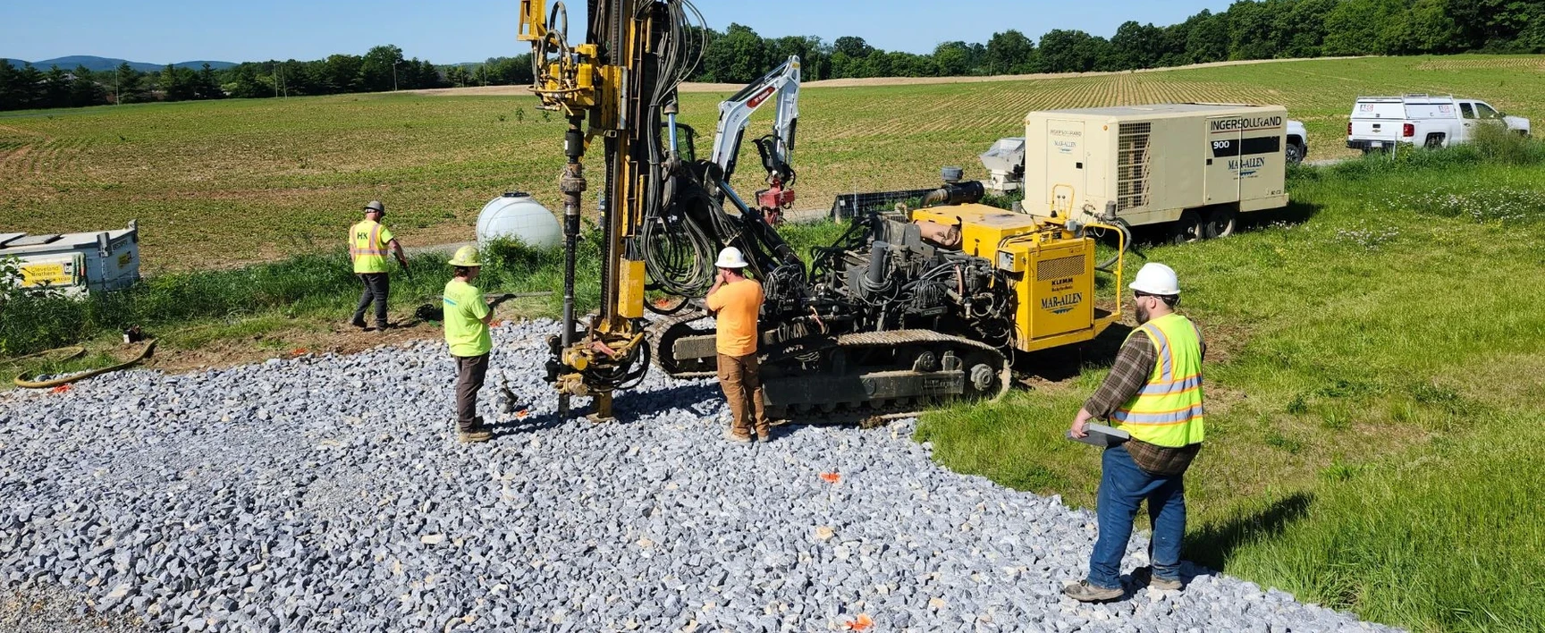 Drilling crew performing subsurface investigations for the Open-End Geotechnical Services Contract, with geotechnical drilling equipment, support vehicles, and field personnel collecting site data.