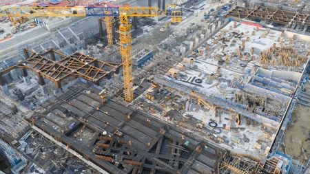Aerial view of a large infrastructure construction site featuring cranes