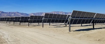 Rows of tilted solar panels arranged in a large solar farm across a dry desert landscape