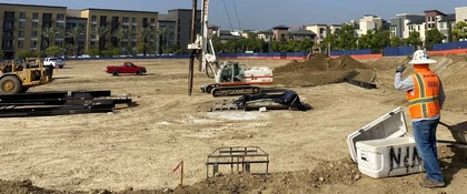 Track-mounted geotechnical drilling rig operating at a large construction site