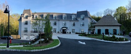Front exterior view of the Mirbeau Inn & Spa hotel and spa facility in Rhinebeck, New York, showcasing the main entrance, landscaped grounds, and guest accommodations.
